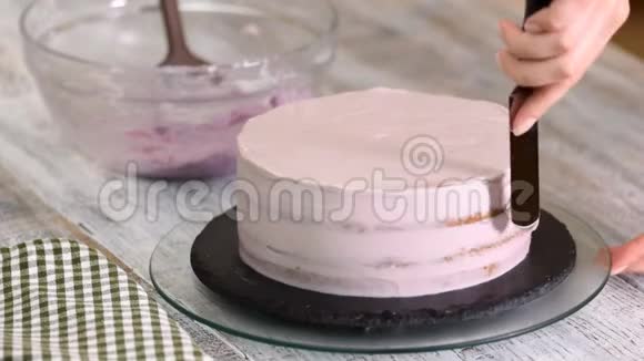 用紫色奶油盖装饰蛋糕的过程甜点师使用糕点抹刀将饼干奶油切等视频的预览图