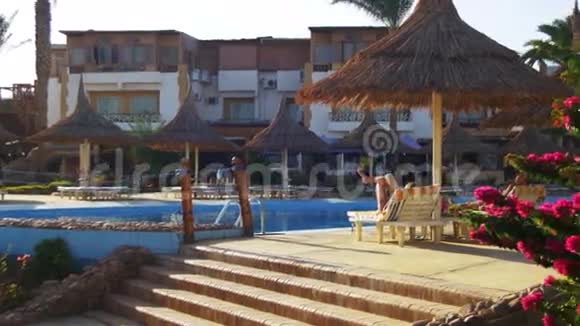 在埃及的蓝色游泳池棕榈树和日光浴的酒店度假村人们在游泳池边晒日光浴视频的预览图
