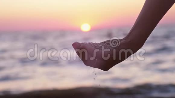在日落时女性用手指在海洋背景下用镜头耀斑斑效应用手倒出慢慢慢慢视频的预览图