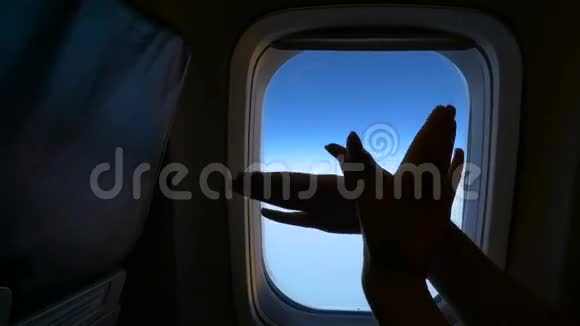 手在飞机窗户的背景上做着飞鸟的手势高清视频的预览图