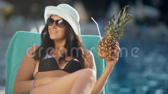 戴太阳镜的漂亮女孩在豪华游泳池里喝新鲜鸡尾酒视频的预览图