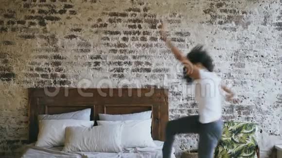 卷曲的混血少女快乐的在家里的床上跳舞视频的预览图
