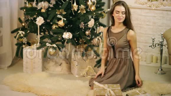 美丽的女人把礼物藏在圣诞树下视频的预览图