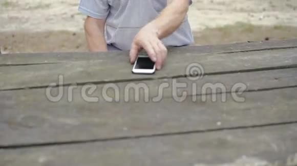 有皱纹的老人在森林里用电话视频的预览图