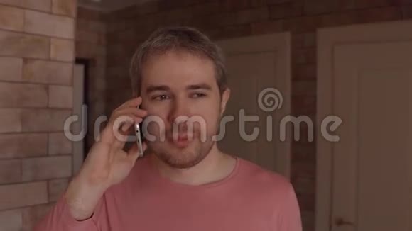 穿着粉红色T恤的帅哥在家里用手机说话4K近距离射击视频的预览图