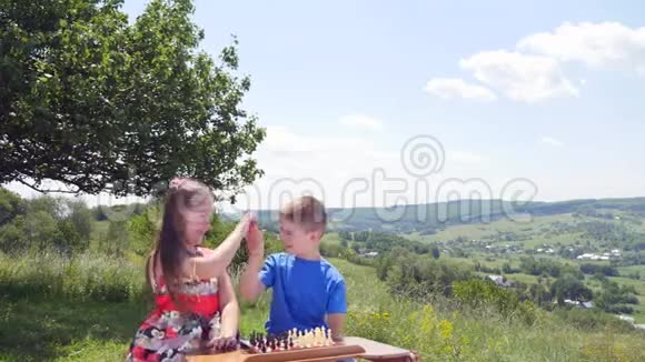 两个男孩和女孩在大自然背景下玩放大镜视频的预览图