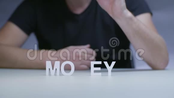 男士双手写字用灰色背景的白色塑料字母写钱视频的预览图