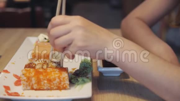 女孩吃寿司和蘸酱在寿司吧关闭视频的预览图