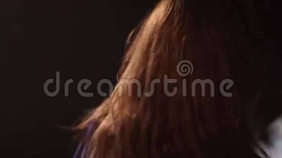 一个女孩在黑暗的工作室里和烟雾跳舞的特写镜头视频的预览图