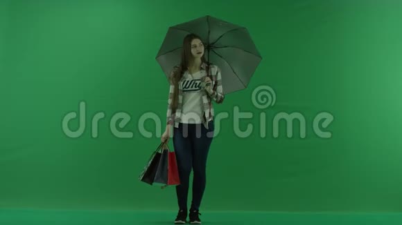 带着包的女孩站在绿色屏幕上的雨伞下视频的预览图