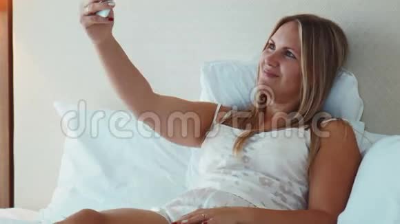 微笑的金发女人带着智能手机的视频游戏视频的预览图