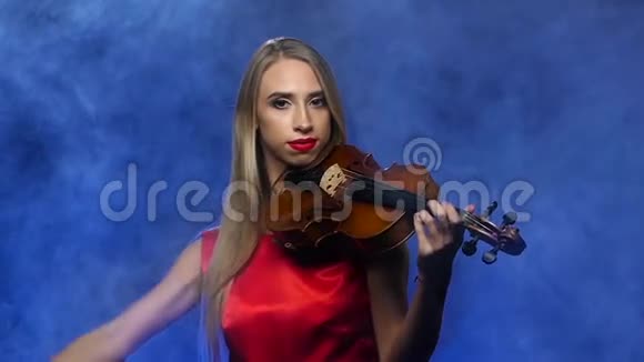 金发女孩拉小提琴烟熏背景慢动作视频的预览图