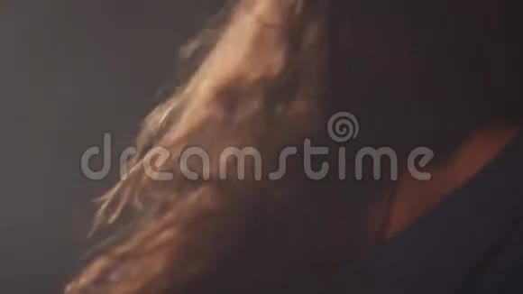一个女孩在黑暗的工作室里和烟雾跳舞的特写镜头视频的预览图