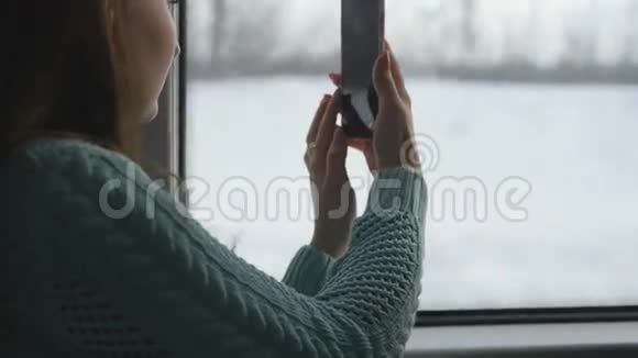 年轻女孩坐火车旅行用手机拍摄窗外的风景美丽美丽视频的预览图