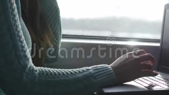 女性手在火车上的笔记本电脑键盘上打字女人在铁路上和朋友聊天少女视频的预览图