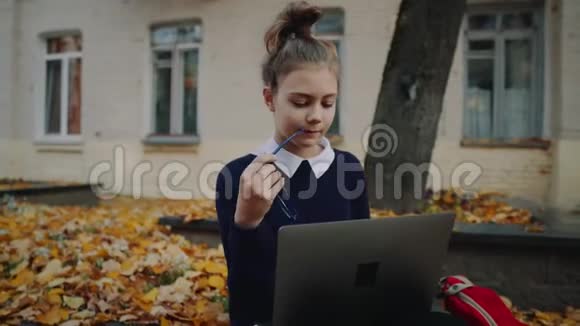 在秋城街的人行道上坐着一个漂亮的时髦少女用手提电脑女生视频的预览图