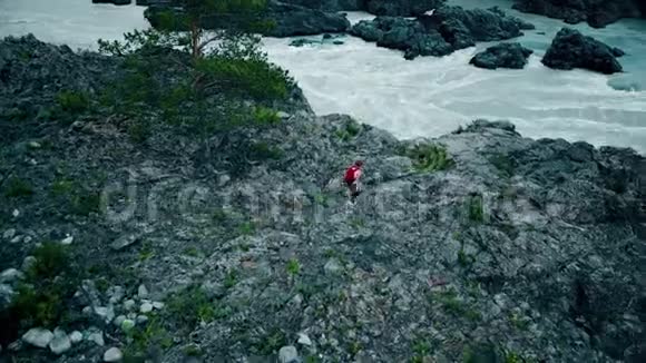 空中飞行带背包的女游客在岩石上到一条山涧女孩旅行者喜欢散步西伯利亚阿尔泰视频的预览图