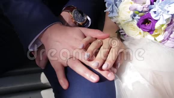 新婚夫妇手里拿着结婚戒指新娘和新郎在鲜花或婚礼花束上戴着结婚戒指新婚夫妇视频的预览图