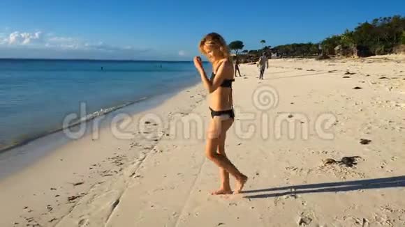 一个穿比基尼的女孩在一个孤独的热带海滩日落时在印度洋游泳视频的预览图