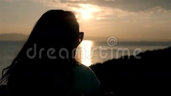 日落时海岸边的年轻美女剪影视频的预览图