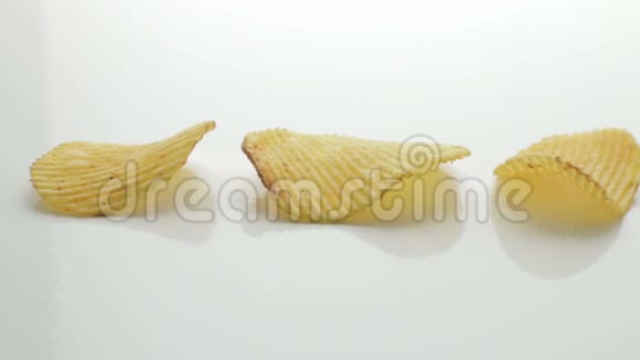 不健康的有害食品黄色美味的土豆肋条脆片连续躺在白色的桌子背景上特写镜头移动视频的预览图