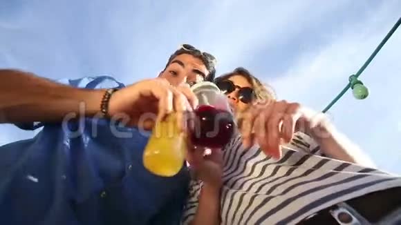 疯狂的年轻夫妇低头看着摄像机喝着鸡尾酒笑着视频的预览图