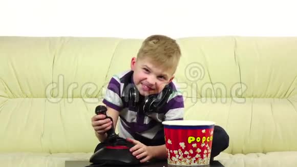 男孩玩操纵杆在线游戏吃爆米花慢动作视频的预览图