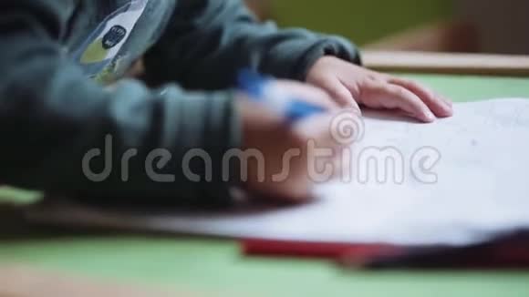 小男孩用铅笔在纸上画画视频的预览图