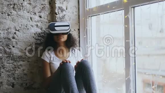 Curly非洲裔美国妇女在家里使用VR360耳机眼镜体验虚拟现实视频的预览图
