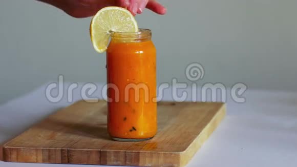女人手在木板上用鲜橙色滑冰沙加入水果视频的预览图