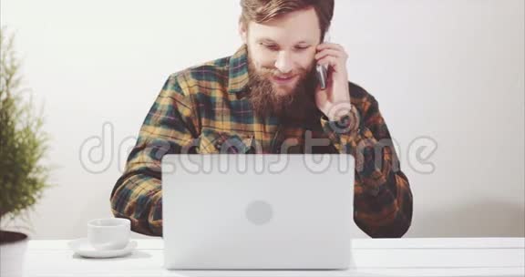 使用笔记本电脑和智能手机交谈的胡子男人视频的预览图