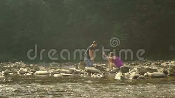 相爱的夫妻在山河上泼水相机镜头中的太阳反射视频的预览图