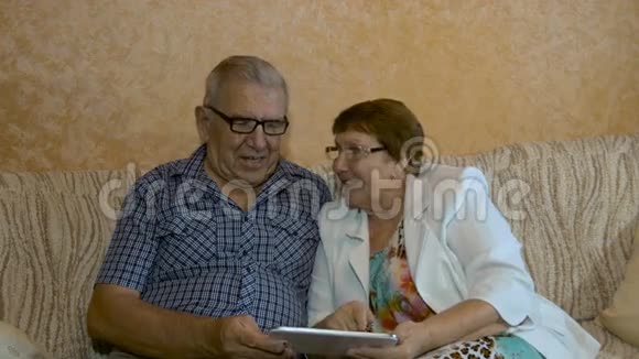 漂亮的老夫妇在你的平板电脑上看照片视频的预览图