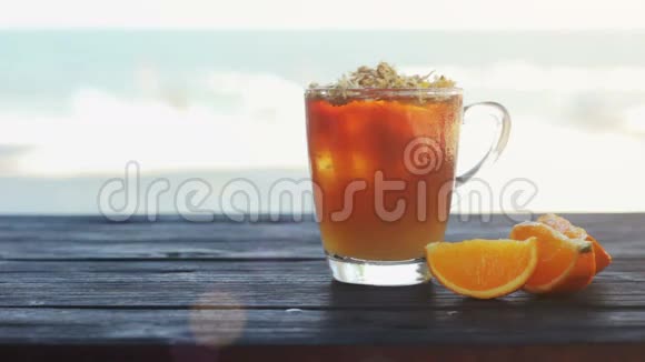 一杯冰茶菊花和橘子黑木桌上的冰块视频的预览图