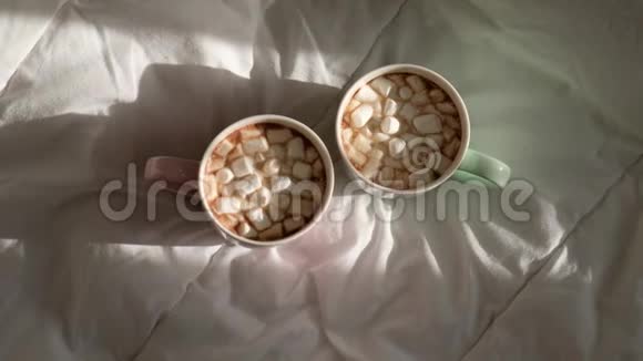 两杯热巧克力和棉花糖在床上早上好世界视频的预览图