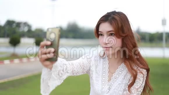 带着智能手机的女人在公园自拍视频的预览图