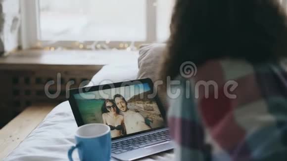 可爱的年轻女性躺在床上与朋友用手提相机在线视频聊天视频的预览图