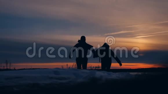 两名游客在夕阳下奔跑剪影滑稽积极的自然景观冬天的雪男摄影师生活方式男视频的预览图