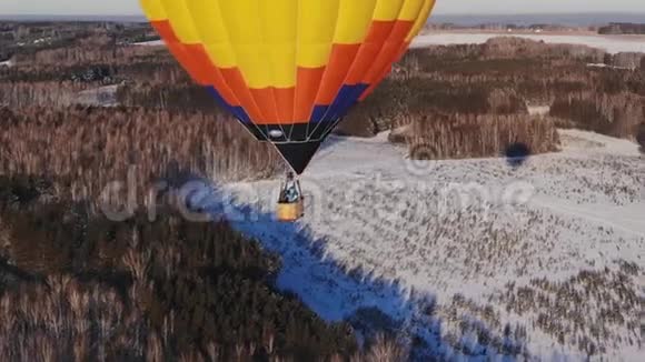 空中拍摄的人们乘坐一个大明亮的气球飞越冬季森林视频的预览图