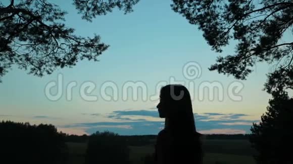 日落后一位年轻女子用手机自拍的剪影视频的预览图