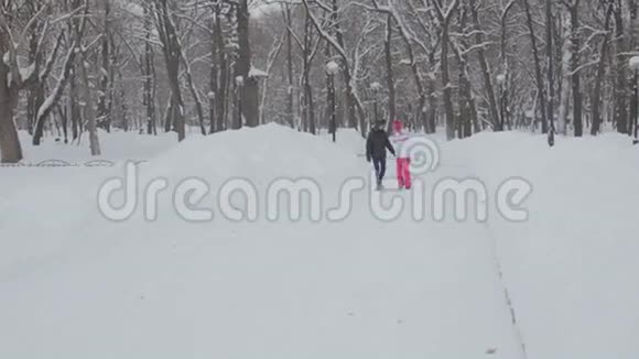 男孩和女孩在白雪覆盖的公园里踏雪视频的预览图