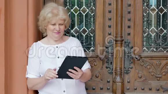 使用平板电脑的老年妇女背景中的老式建筑视频的预览图