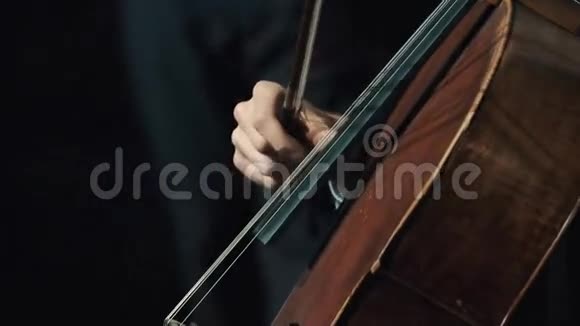 在黑暗的房间里男人用手握着小提琴手指拉着大提琴弦视频的预览图