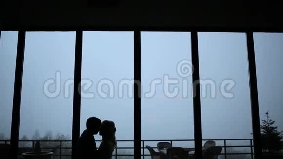一对夫妇在大的全景窗户和雾的背景下接吻视频的预览图