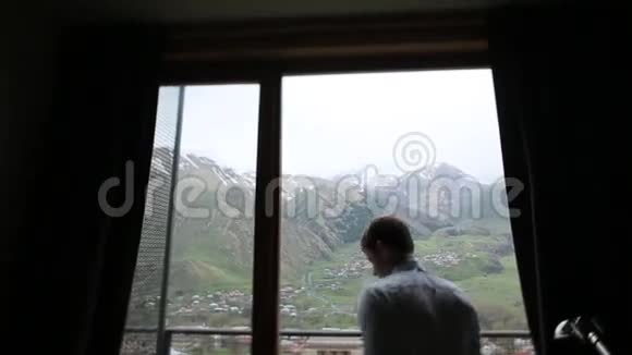 站在窗前的人站在山上的背景上视频的预览图