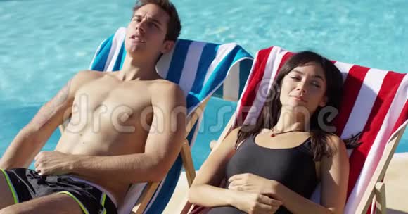 年轻夫妇在甲板椅上放松池边视频的预览图