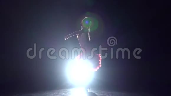 女孩在黑暗的背景上用灯光照明器跳舞慢动作视频的预览图