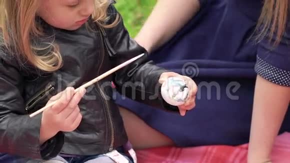 小可爱的女孩在公园的父母附近画复活节彩蛋慢慢地视频的预览图