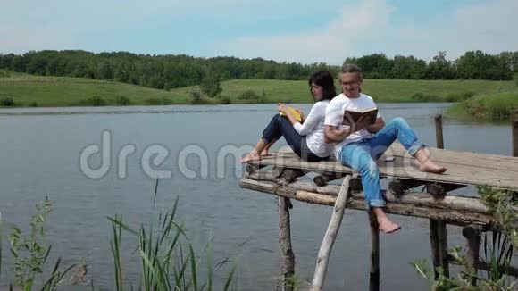 男人和女人在湖边的桌上看书视频的预览图