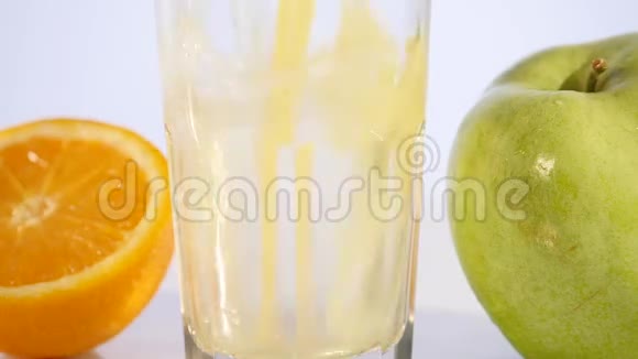 在彩色背景上倒入橙汁和苹果汁视频的预览图